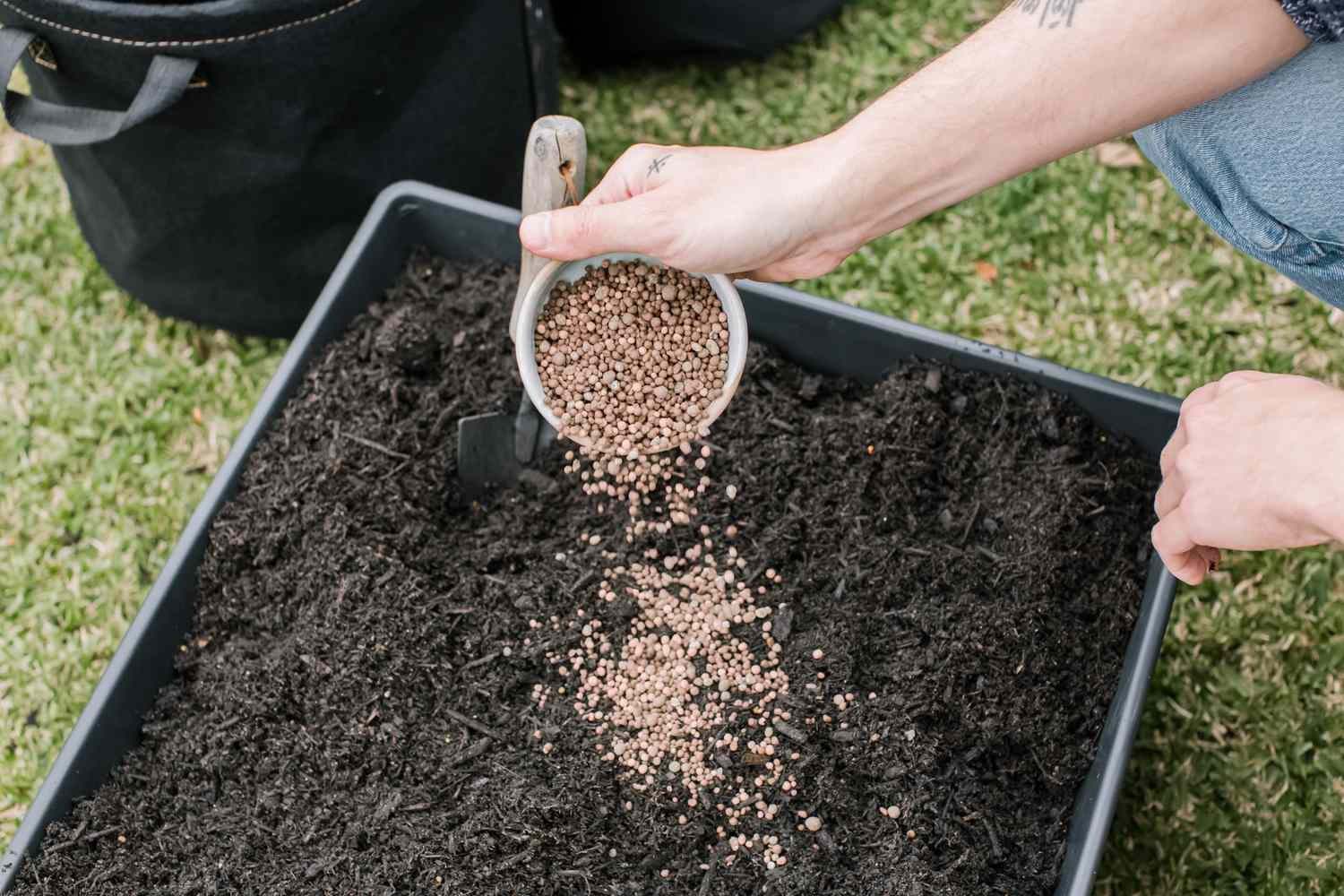 Pellets de abono marrón siendo añadidos a la tierra para macetas