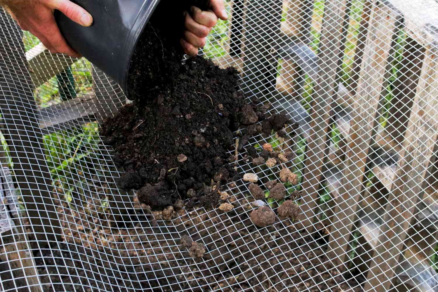 Compost vertido sobre un tamiz metálico para tamizar y cosechar el compost listo 